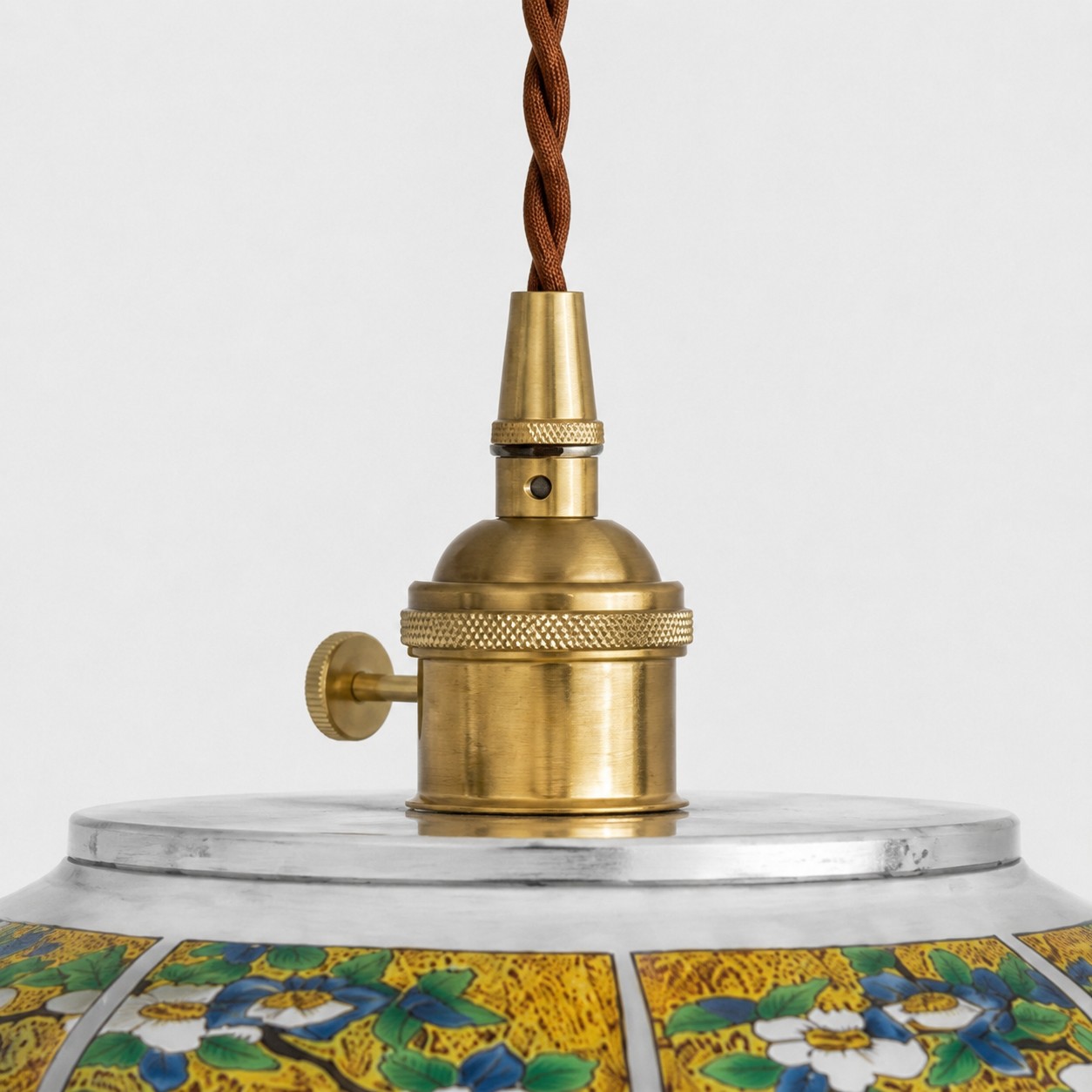 Brass-tone lamp holder and twisted brown cord close-up