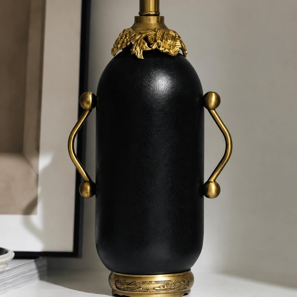 Close-up of matte black table lamp with antique brass-toned handles